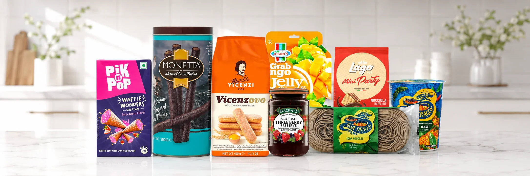 Assorted international gourmet snacks and FMCG products including wafers, jelly, pasta, and preserves on kitchen counter