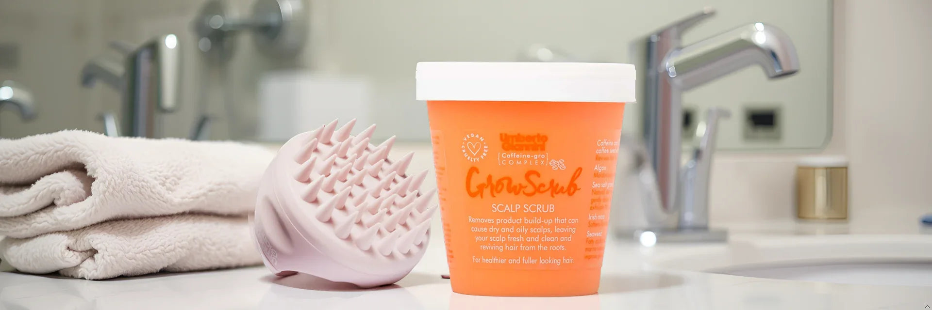 Umberto Giannini GrowScrub scalp scrub with pink massager on bathroom counter, vegan & cruelty-free hair care