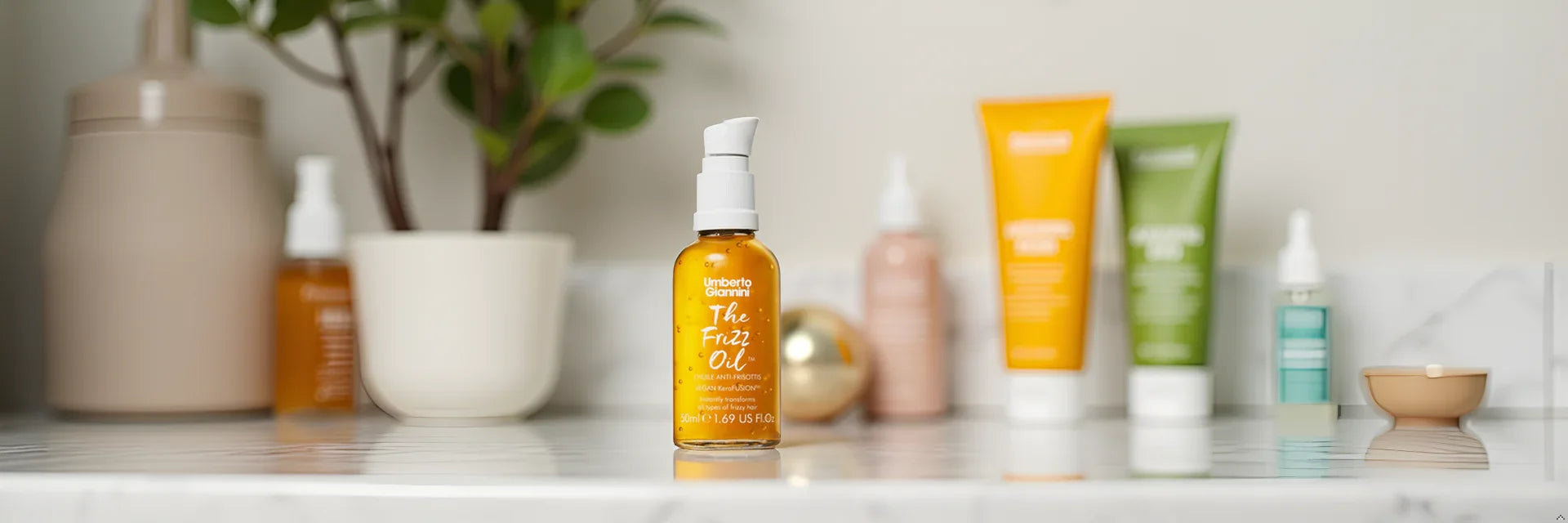 Umberto Giannini The Frizz Oil for frizzy hair, vegan hair care on marble shelf with beauty products