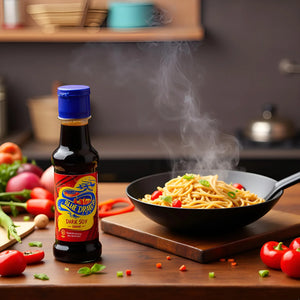 Steaming bowl of noodles with cherry tomatoes and scallions beside a bottle of Blue Dragon dark soy sauce on a wooden kitchen counter