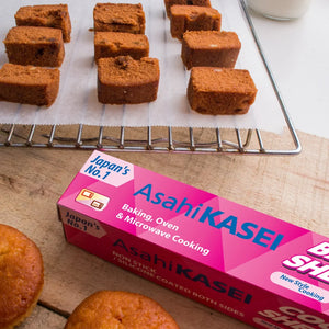Asahi Kasei baking and cooking sheet box on a table with baked cake slices and muffins.