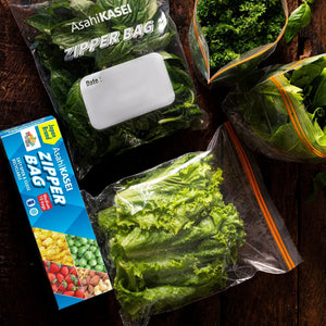 Reusable zipper bags filled with leafy greens on a wooden surface, box packaging visible