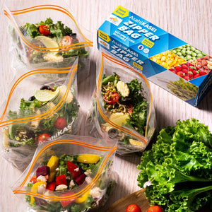 Clear zipper bags filled with fresh salad vegetables near packaging box on a wooden surface