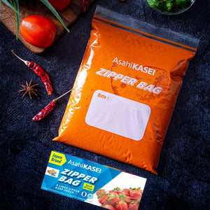 Small Asahi Kasei zipper bag filled with orange marinade, fresh tomatoes, and spices nearby.