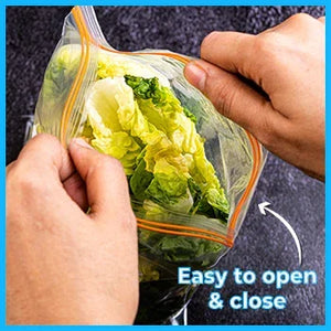 Hands opening a small clear zipper storage bag with lettuce, easy to open and close text