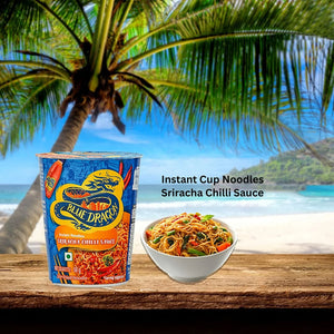 Blue Dragon Sriracha Chilli instant cup noodles and bowl of noodles on wooden table by beach with palm tree