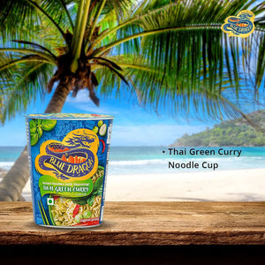 Blue Dragon Thai Green Curry instant noodle cup on wooden table by tropical beach with palm tree
