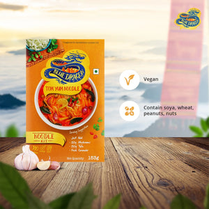Blue Dragon Tom Yum Noodle Kit box on wooden table with garlic cloves, vegan and allergen info