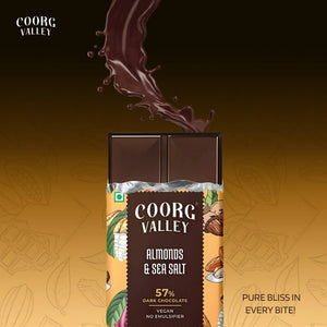 Coorg Valley 57% dark chocolate bar with almonds and sea salt, unwrapped, on a gold background.