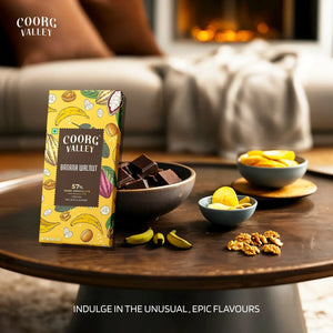 Coorg Valley Banana Walnut dark chocolate bar with banana slices, walnuts, and chocolate pieces on a table.