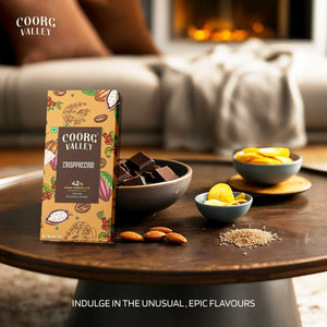 Coorg Valley 42% dark chocolate crisppaccino bar with bowl of chocolate pieces, almonds, and dried fruit on wooden table