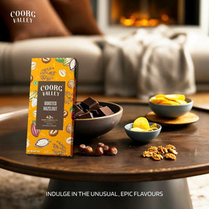 Coorg Valley roasted hazelnut 42% dark chocolate bar with chocolate pieces and nuts on wooden table