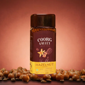 Coorg Valley Vanilla Hazelnut instant coffee jar with hazelnuts on a brown background