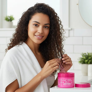 Woman in white robe applying Curl Jelly Mask hair treatment from pink container in bright bathroom