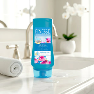 Finesse Normal Conditioner bottle with hyaluronic acid, camellia oil, keratin on bathroom counter with towel and orchid