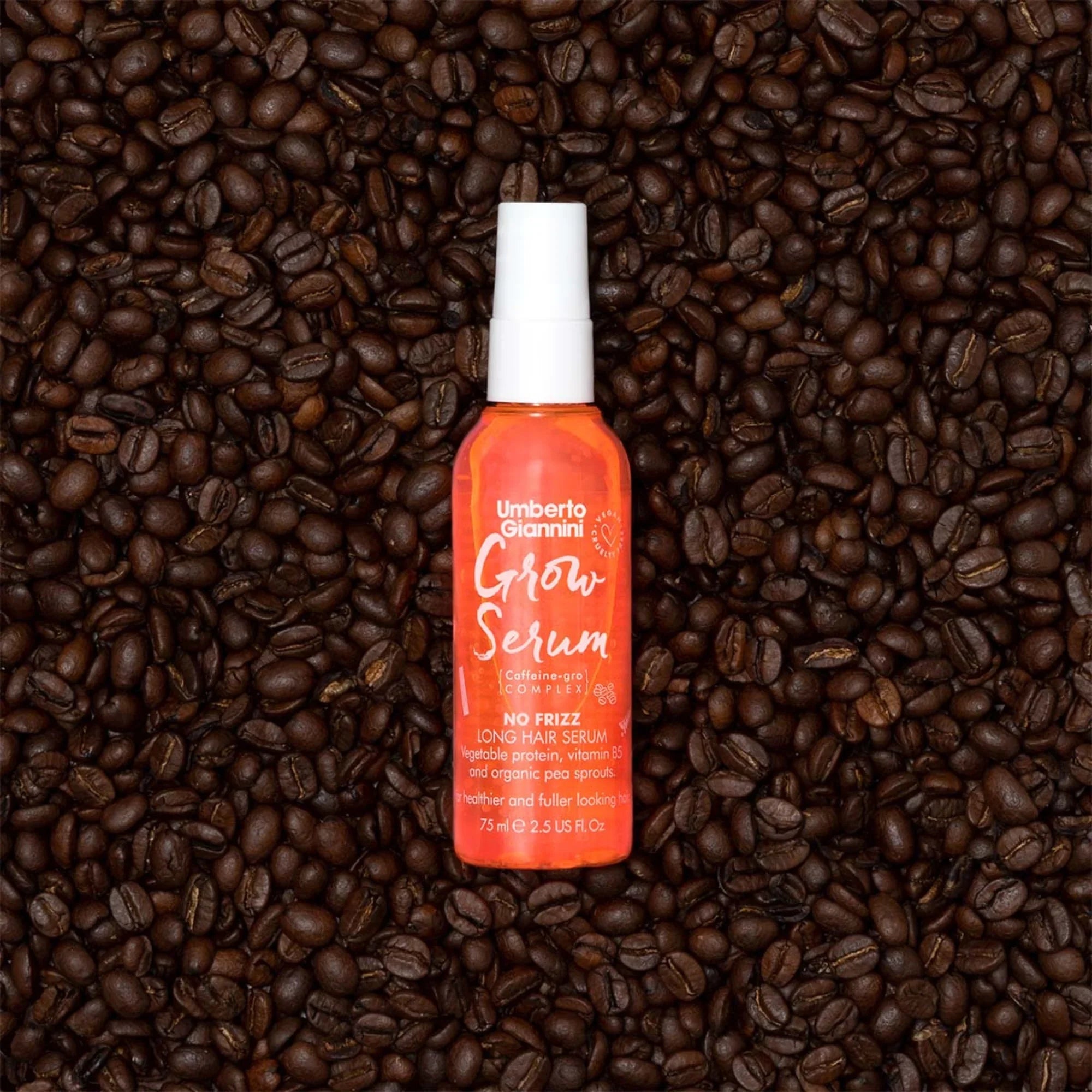 Umberto Giannini Grow Serum orange bottle on dark roasted coffee beans background, long hair serum with caffeine complex