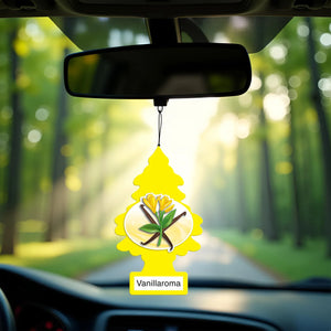 Yellow Little Trees Vanillaroma car air freshener hanging from rearview mirror with forest road background