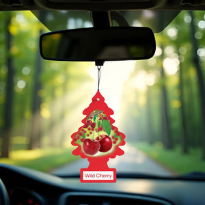 Red Little Trees Wild Cherry car air freshener hanging from rearview mirror in a sunlit forest road setting