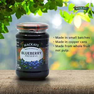 Mackays blueberry preserve jar on textured surface with green leaves and product features in background