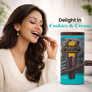 Woman enjoying cookies and cream wafer stick next to a tin of Monetta luxury cream wafers