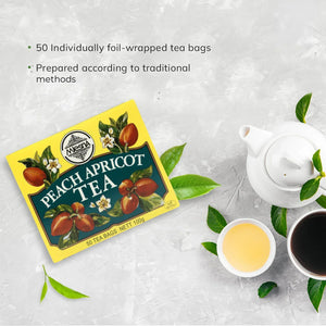 Peach apricot tea box with 50 tea bags, teapot, two tea cups, and tea leaves on a light background