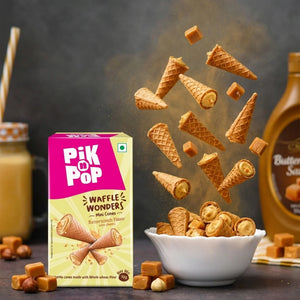 Mini butterscotch waffle cones with caramel chunks, box, and sauce bottle on a table.