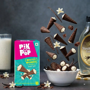 Chocolate mini waffle cones with vanilla filling in bowl, product box, vanilla flowers, syrup