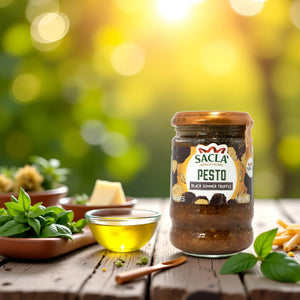 Jar of Sacla Black Summer Truffle pesto on wooden table with basil, olive oil, cheese, and pasta