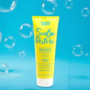 Yellow tube of Umberto Giannini Scalp Restore Balancing Shampoo with bubbles on blue background