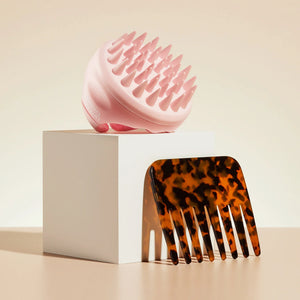 Pink silicone scalp scrubber and tortoiseshell hair detangling comb displayed on white block
