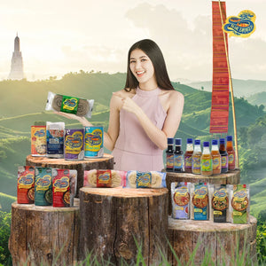 Smiling woman in pink dress presenting Blue Dragon Asian food products on wooden logs with green hills background