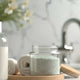 Bath and body wash bottles, bath salts jar, and rolled towels on a bathroom counter
