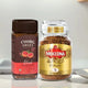 Instant coffee jars of Coorg Valley Blood Orange and Moccona Classic beside a steaming cup in a modern kitchen