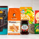 Assorted international gourmet snacks and FMCG products including wafers, jelly, pasta, and preserves on kitchen counter