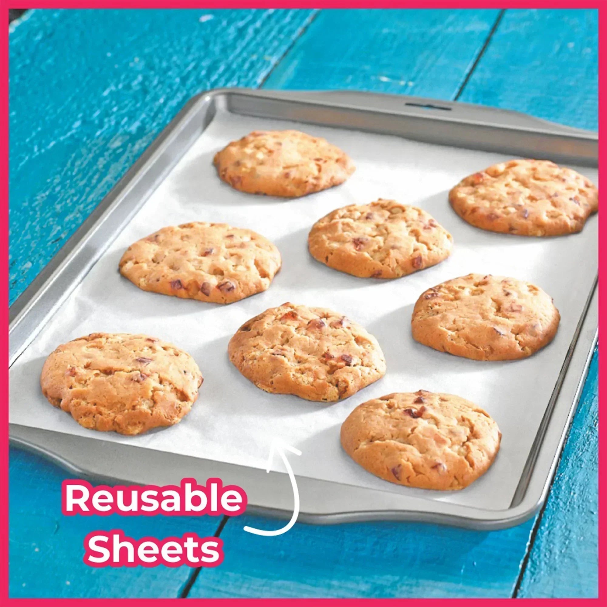 Baking tray with cookies on a reusable nonstick baking sheet, blue wooden table background