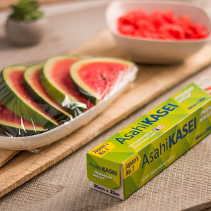 Plastic food wrap box beside sliced watermelon in a tray covered with cling film
