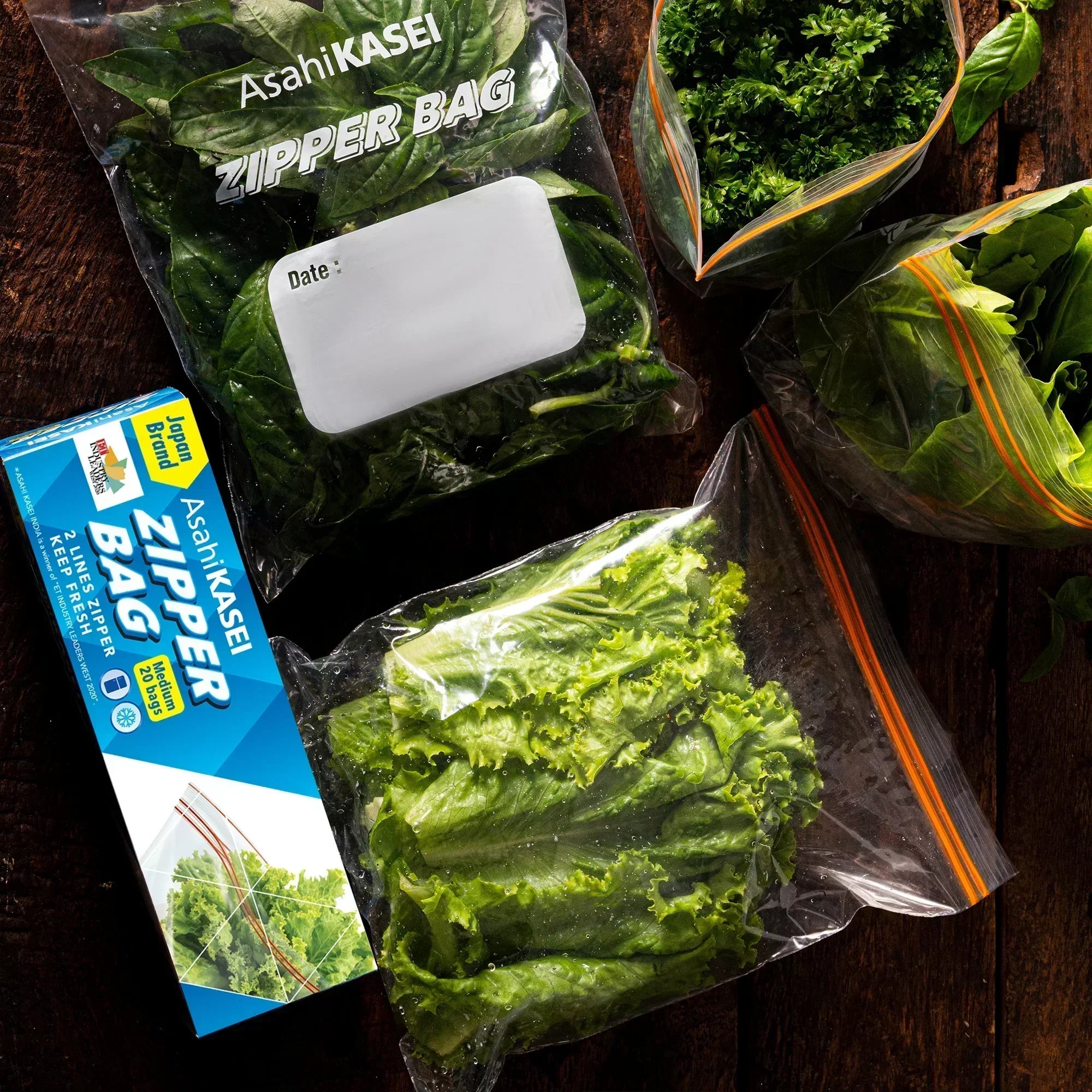 Assorted green vegetables stored in clear zipper bags on a wooden surface