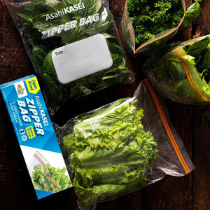 Assorted green vegetables stored in clear zipper bags on a wooden surface