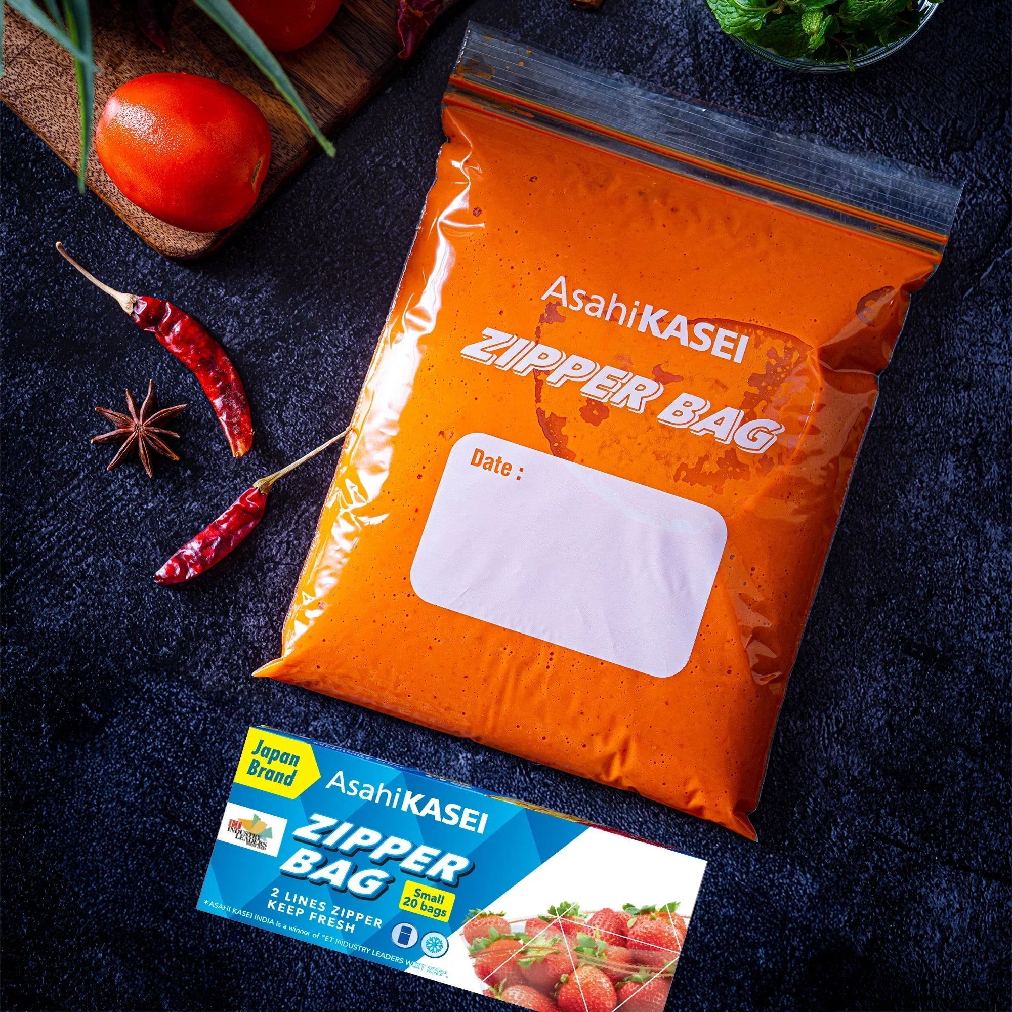 Small Asahi Kasei zipper bag filled with orange marinade, fresh tomatoes, and spices nearby.