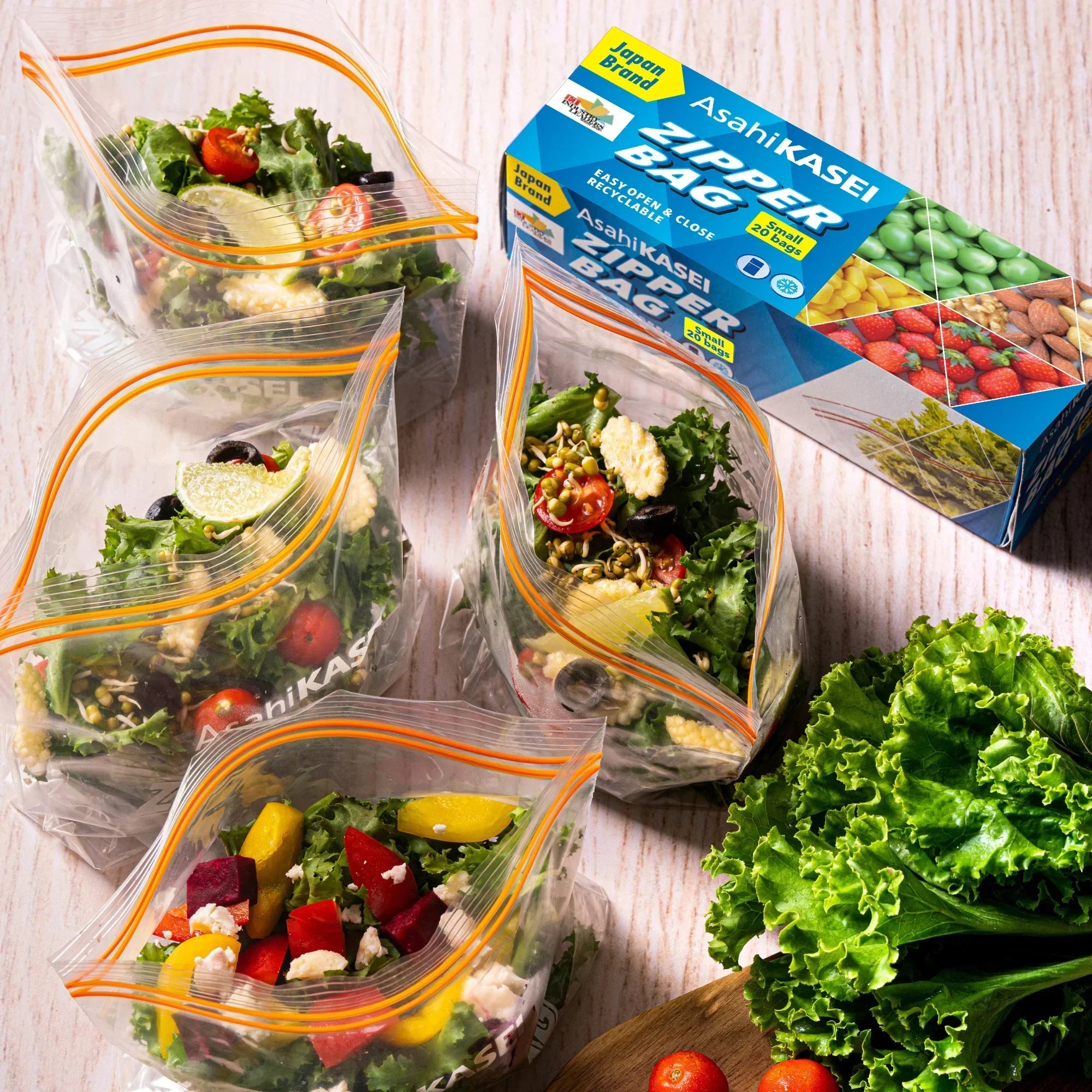 Clear zipper storage bags filled with fresh salad near a box labeled Zipper Bag, with lettuce and tomatoes.