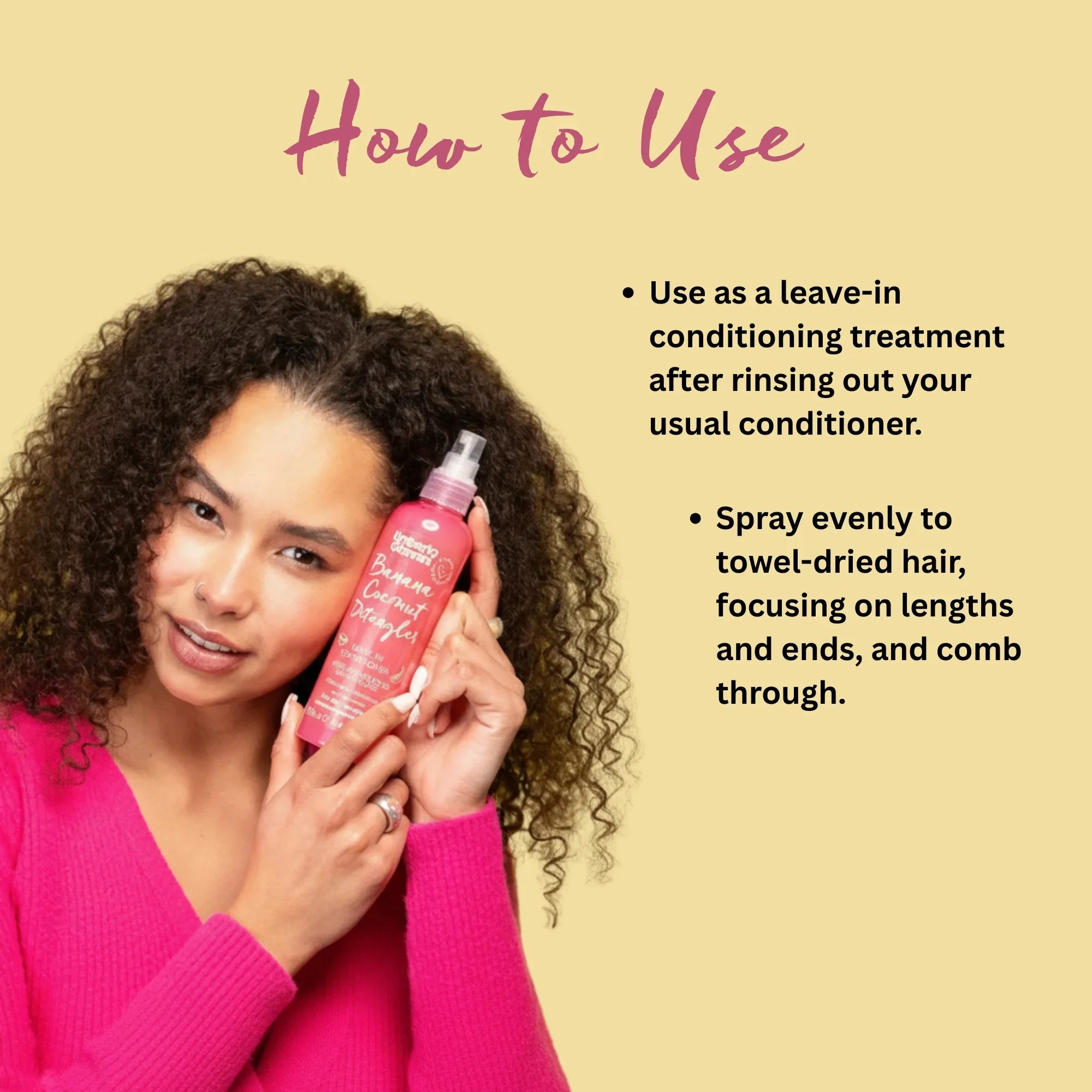 Curly-haired woman in pink sweater holding Banana Coconut Detangler conditioner spray bottle with usage instructions