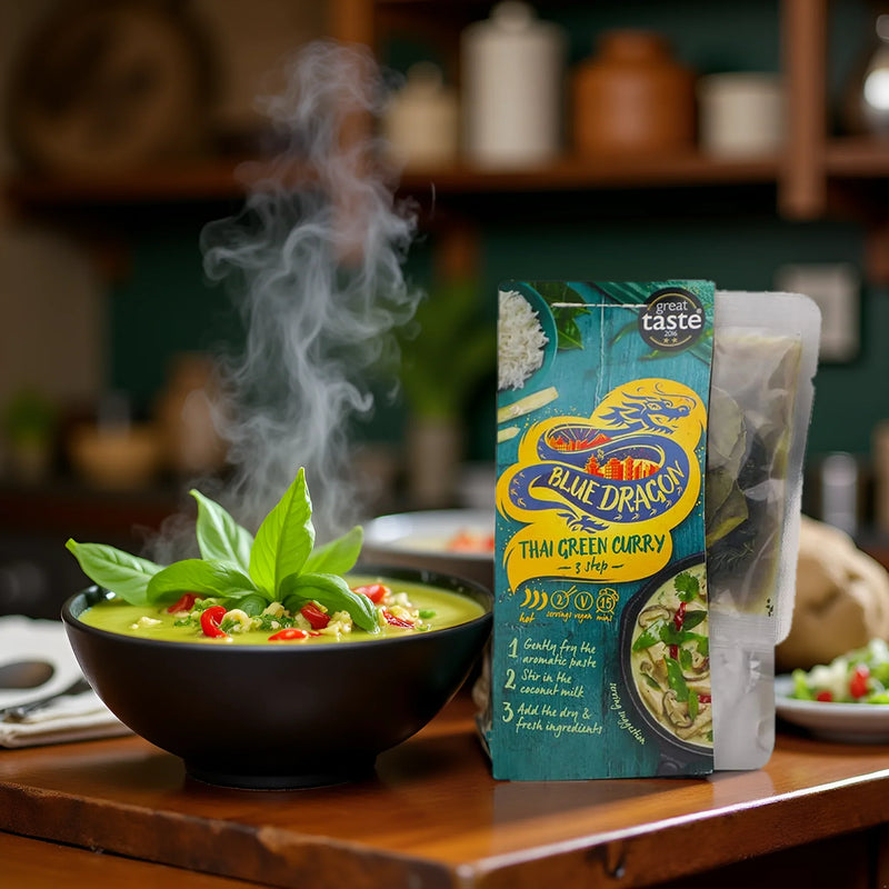 Blue Dragon Thai Green Curry kit with steaming curry bowl, basil, and chili garnish on table