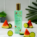 Bodycology cucumber melon fragrance mist bottle with watermelon and cucumber slices on a white surface.