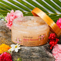 Jar of body scrub with cherry blossom design on a natural background with flowers and leaves.