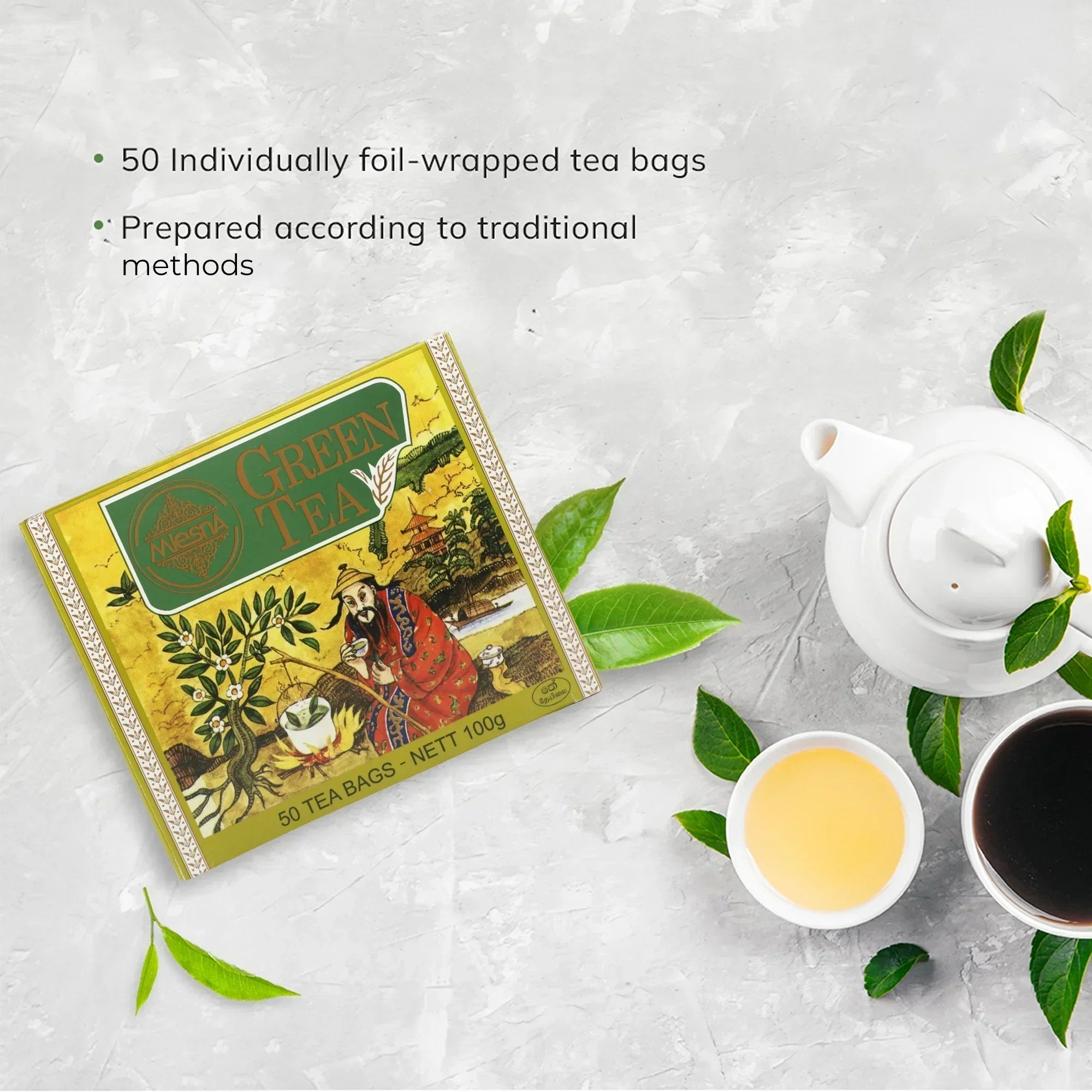 Chinese green tea 100g box with teapot, teacups, and tea leaves on a light surface