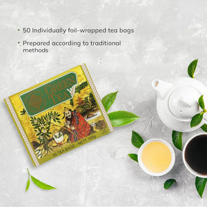 Chinese green tea 100g box with teapot, teacups, and tea leaves on a light surface
