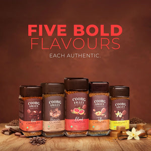 Five Coorg Valley instant coffee jars in assorted flavors, arranged on a rustic wooden table.