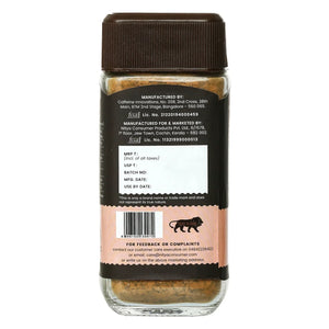 Back view of a glass jar with brown powder, black label, and product information panel.