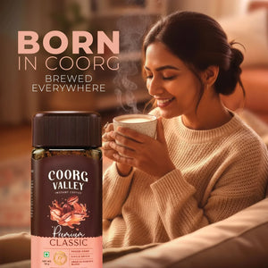 Woman enjoying a cup of hot coffee with Coorg Valley Premium Classic instant coffee jar in foreground.