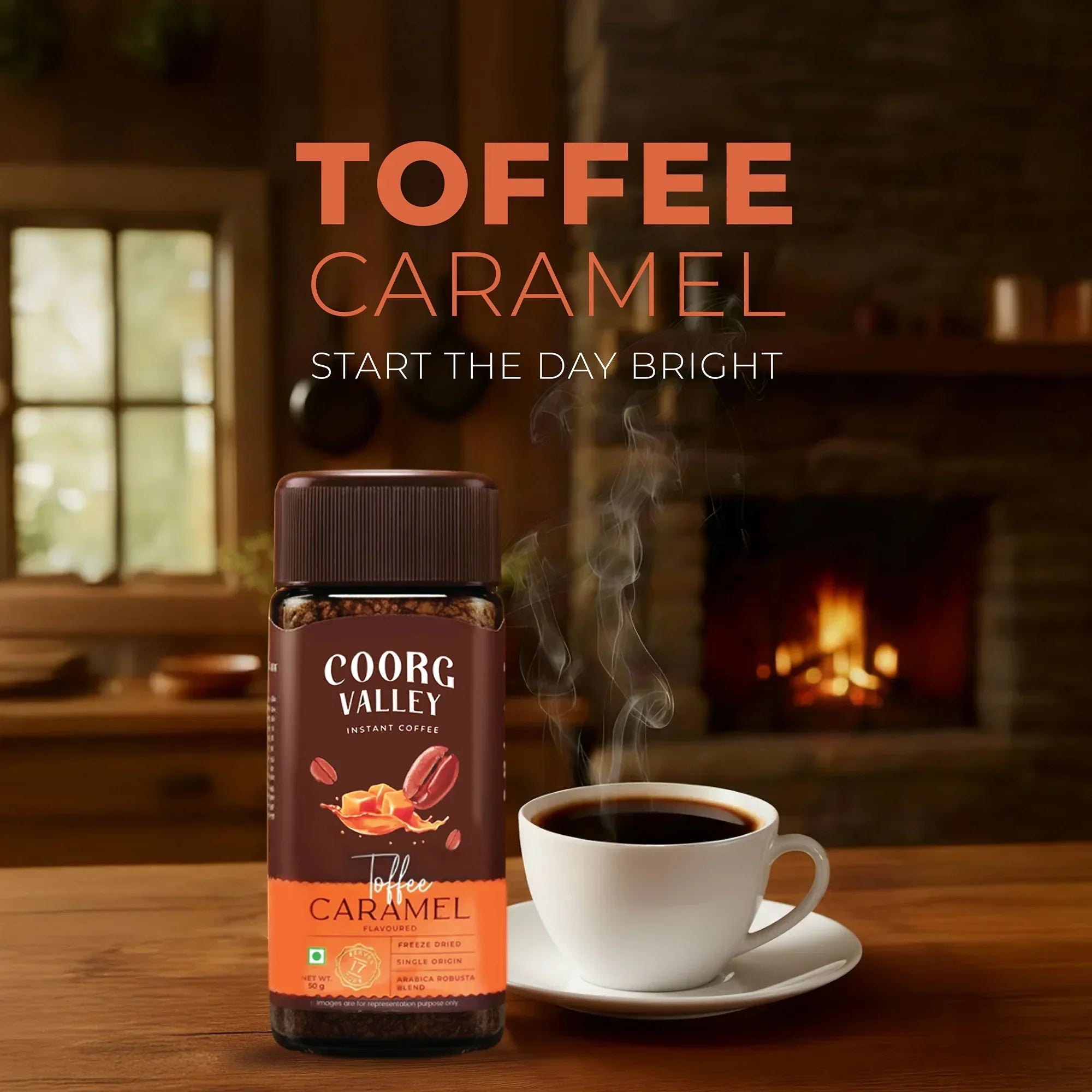 Coorg Valley toffee caramel instant coffee jar beside steaming cup in cozy room with fireplace.